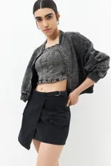 Minifalda de jean celeste con corte asimétrico, bolsillos de parche con solapa y tiras ajustables con hebillas en los laterales.