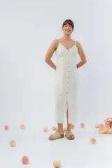 Vestido midi celeste de tejido tipo seda fría, con breteles finos regulables, botones de madera decorativos en el frente, pliegues decorativos en la cintura y cierre invisible en el costado.