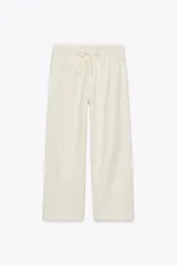 Pantalón jogger color beige claro, de tiro medio, con cintura elástica ajustable con cordones y bolsillos laterales ocultos. Presenta una pierna ancha y está confeccionado con hilatura de algodón y lyocell.