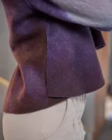 Sweater de lana merino afieltrada color uva con teñido artesanal tie dye en forma de luna. Tiene cuello alto cruzado y aberturas laterales traseras.