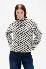 Sweater de tejido jacquard con diseño geométrico de líneas entrelazadas en tonos negro y marrón. Presenta cuello alto, mangas largas con terminación holgada y un corte recto.