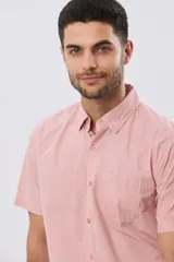 Camisa lisa de algodón azul marino, de manga corta, con cuello camisero, cierre frontal de botones y un bolsillo aplicado en el pecho.