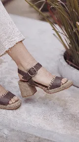 Sandalia Bruna de cuero y gamuza en tonos marrones y beige, con taco ancho, plataforma y tira al tobillo con hebilla metálica.