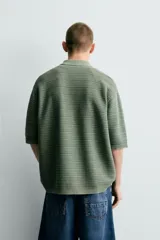 Polo de punto de algodón con textura acanalada, color verde militar, efecto lavado, cuello solapa, cierre frontal con botones y mangas cortas holgadas.