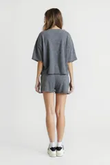 Remera gris de corte cropped con cuello redondo y manga corta. Estampado rectangular en el pecho con texto "Western Avenue Champions".