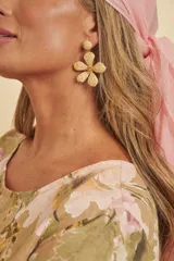 Aros colgantes de diseño floral elaborados en rafia de color beige, con detalle central dorado.