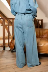 Pantalón de denim celeste con corte amplio y cintura elastizada. Presenta detalles de pedrería en los laterales.