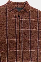 Blazer de cuello subido y manga larga, con diseño peplum en el bajo y cierre frontal con botones. Confeccionado en tejido texturizado a cuadros.