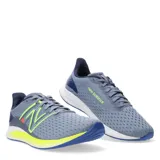 Championes de running New Balance modelo DynaSoft Lowky RC, color gris con detalles en amarillo neón y azul. Presentan capellada de malla transpirable, logo N lateral en contraste y entresuela con tecnología DynaSoft para mayor amortiguación.