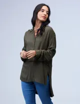 Blusa verde militar en crepe, marca Cupio. Cuello a la base, escote en V y abertura con botones. Manga larga de largo regulable con presilla y botón. Largo de espalda mayor al largo delantero.