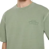 Remera verde claro de manga corta con pequeño estampado circular en el pecho, de corte holgado.