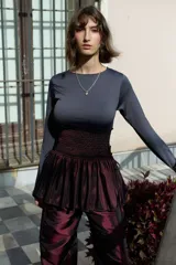 Minifalda negra de tafeta con cintura alta elastizada, diseño con volado y lazos laterales ajustables.