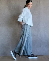 Pantalón de jean azul de tiro medio, con corte wide leg y ruedo deshilachado.