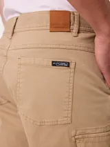 Bermuda cargo de gabardina color beige, con bolsillos laterales con fuelle en las piernas, bolsillos delanteros tipo ojal y traseros. Cuenta con presillas para cinto y cierre frontal con botón y cierre.