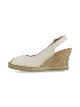 Sandalia de cuero napa color crema, tipo alpargata con cuña de yute, punta cerrada y tira ajustable al tobillo con hebilla.