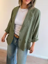 Blazer de lino color beige, de corte relajado y líneas clásicas. Presenta cuello con solapas, cierre frontal con dos botones y bolsillos con solapa en el frente.