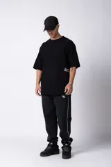 Remera de corte oversize color negro, con cuello redondo y mangas cortas. Presenta un pequeño estampado en color blanco en la parte inferior lateral con la frase 'Curbside Treasures'.