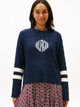 Sweater de punto trenzado Tommy Hilfiger color azul marino, de manga larga y cuello redondo. Presenta un gran logo gráfico bordado en el pecho y bandas blancas en las mangas.