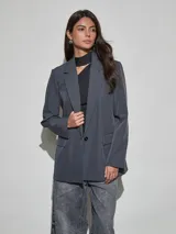 Blazer gris oscuro de corte recto y holgado, con solapas de muesca, un botón frontal y bolsillos con solapa en los laterales.