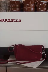 Cartera tipo bandolera de gamuza color negro, con cierre superior, tiras colgantes decorativas y herrajes metálicos plateados. Incluye asa corta para llevar al hombro y correa larga ajustable y desmontable.