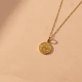 Conjunto compuesto por una cadena fina de eslabones y un dije circular con la imagen de San Benito, ambos realizados en oro 18k.