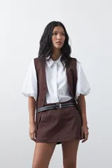 Short pollera de tiro medio con silueta recta y diseño tipo falda en el frente, confeccionado en tela de sastrería color marrón.