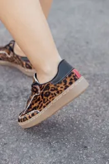 Zapatillas bajas con estampado animal print de leopardo, con cordones negros y suela color caramelo.