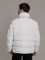 Campera puffer Calvin Klein acolchada, de color gris claro, con cuello alto, cierre frontal con cremallera negra y bolsillos laterales con cierre.
