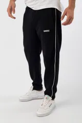 Pantalón de jogging negro con una franja vertical blanca a los costados y logo de la marca en la pierna izquierda.