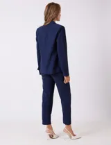 Blazer sastrero entallado color beige, con cuello de solapa, cierre frontal con un botón a tono y hombreras estructuradas. Presenta bolsillos laterales con solapa y forro interno.