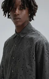 Camisa de manga corta con calce oversize, confeccionada en algodón con bordado tipo broderie y acabado con efecto desgastado. Presenta cuello clásico y cierre frontal con botones.