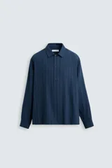Camisa polo de manga larga con cierre frontal de botones, confeccionada en tejido con textura de rayas verticales sutiles.