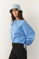 Buzo celeste cropped de manga larga con puños y cordones ajustables en la cintura.
