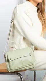 Bandolera de símil cuero color verde menta, con apertura central de cierre, bolsillo principal con cierre metálico y bolsillo frontal con tapa y broches magnéticos. Incluye bolsillos internos y posterior, y correa de galón combinada larga y regulable.