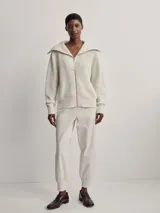 Campera larga tejida color crema con cierre frontal, cuello alto y diseño texturizado.