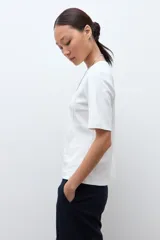 Remera blanca de manga corta con cuello redondo y costuras verticales decorativas en el frente.