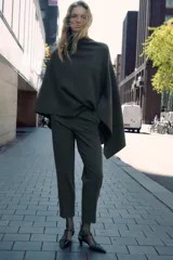 Pantalón tobillero gris oscuro de tiro alto con costuras marcadas en delantero y espalda, bolsillos delanteros de vivo y cierre frontal con cremallera, botón interior y gancho metálico.