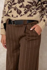 Pantalón de corte ancho y tiro alto, confeccionado en tejido azul marino con finas rayas verticales de hilo de lurex plateado. Presenta cintura con pasacintos y se incluye un cinturón negro con hebilla metálica.