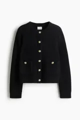 Cárdigan corto negro de punto acanalado, con cuello redondo, manga larga y botones metálicos dorados en el frente. Posee bolsillos de parche con botón en la parte inferior delantera.