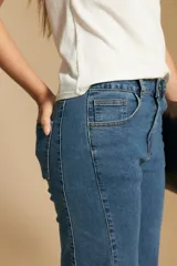 Jean de corte recto y tiro medio, confeccionado en denim elastizado de color negro. Presenta un diseño clásico con cierre de botón y cremallera, bolsillos laterales y traseros, y ruedo con terminación deshilachada.