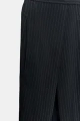 Pantalón de tiro medio con diseño wide leg, confeccionado en tejido con viscosa. Presenta un patrón de rayas diplomáticas, bolsillos laterales ocultos y detalle de pinzas pronunciadas en el delantero. Cierre frontal con cremallera, botón y ganchos metálicos.