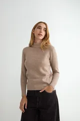 Buzo de punto color crema con cuello alto, manga larga y puños y ruedo acanalados.
