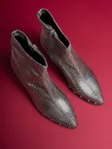 Botas cortas plateadas con textura de piel de serpiente, taco cuadrado y cierre lateral.