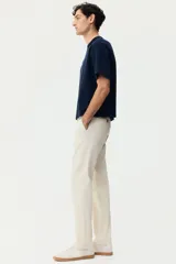Pantalón chino de sarga elástica de algodón, con cierre de cremallera y botón, bolsillos laterales al bies y bolsillos traseros con botón. Presenta un corte ajustado que define la silueta.