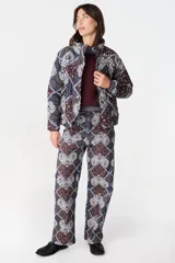 Campera de abrigo con cuello alto y manga ranglan, confeccionada en tela capitoneada con relleno y forro interno. Presenta un diseño estampado con motivos geométricos y paisley en tonos azules y marrones.