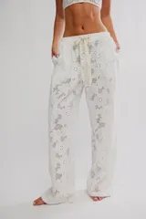 Pantalón blanco de algodón con diseño de bordados tipo broderie con motivos florales, corte holgado de pierna ancha, tiro medio con cintura elástica y cordón ajustable.
