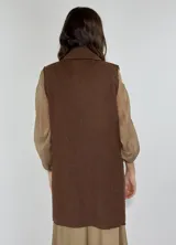 Chaleco largo color beige, con cuello solapa, un botón frontal y dos bolsillos de parche. Presenta costuras decorativas en contraste.