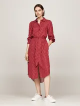 Vestido camisero midi rojo con estampado geométrico blanco, cuello camisero, manga larga con puños abotonados, cinturón anudable y abertura frontal.