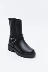 Bota tipo biker de caña media en cuero sintético negro, con panel elástico lateral, suela gruesa dentada y arnés decorativo con herraje metálico.