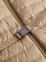 Campera color beige de nailon reciclado, con cuello alto, capucha con cordón ajustable, cierre de cremallera frontal, bolsillos laterales con cremallera, cinturón con hebilla metálica y logo de Calvin Klein en el pecho.